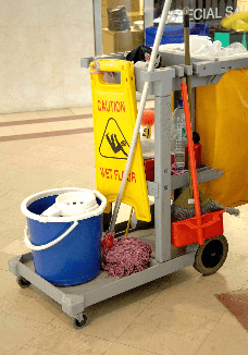 Mobile cart of industrial cleaning supplies and caution sign, including a bucket, mop, and miscellaneous supplies.