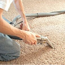 Close up of a cleaning technician power cleaning a beige carpet.